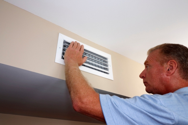 Homeowner inspecting wall air vent duct