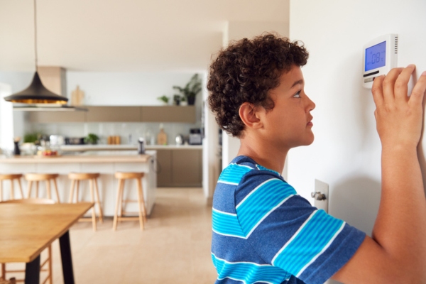 Young boy fidgeting with AC thermostat