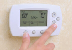 image of a homeowner adjusting thermostat depicting setback thermostat