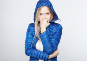 image of a homeowner feeling chilly due to poor heating pump performance in winter