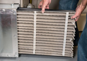senior man changing a dirty air filter in a furnace