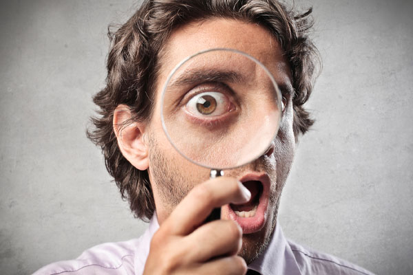 close up of a man looking through a magnifying glass depicting top signs of poor indoor air quality