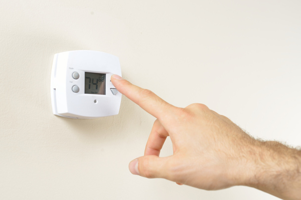 hand adjusting home thermostat