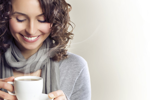 homeowner drinking hot tea while wearing a sweater in winter depicting heat pump auxiliary heat