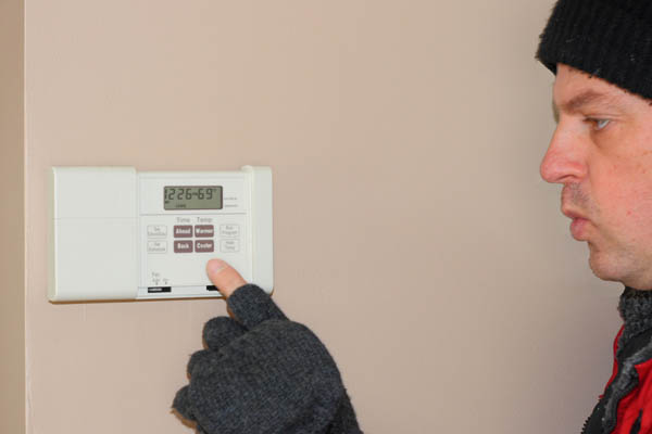 image of a homeowner adjusting a programmable thermostat for boiler