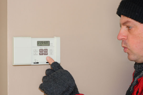 image of a homeowner adjusting heat pump thermostat setting