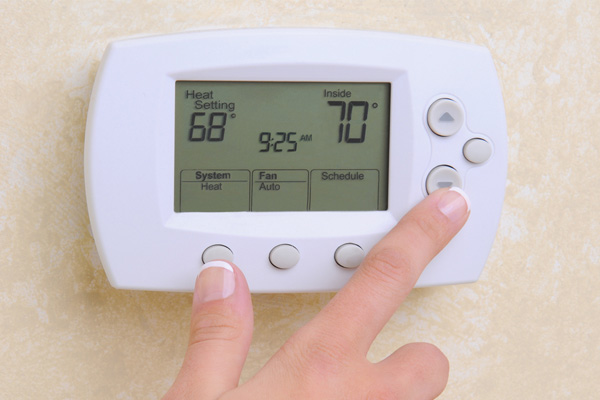 image of a homeowner adjusting thermostat depicting setback thermostat