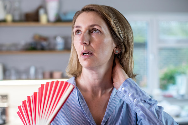 image of a homeowner feeling hot due to air conditioner starting cold and then blowing warm air