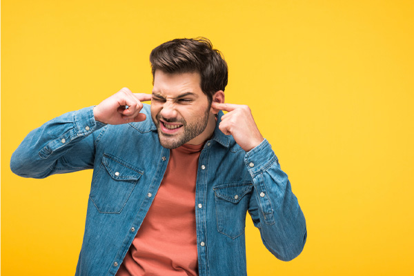 image of a homeowner plugging ears due to air conditioner noise