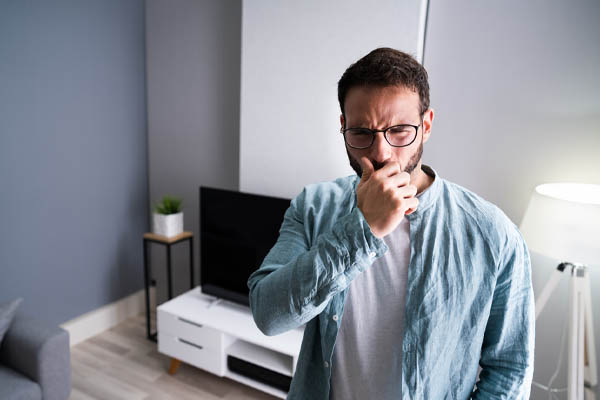 image of a homeowner plugging nose due to furnace odor and overheating