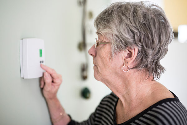 image of a woman at thermostat experiencing thermostat problems