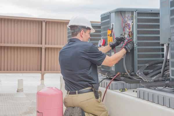 image of an hvac contractor performing heat pump maintenance
