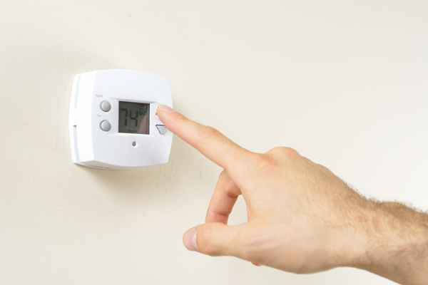 image of hand adjusting thermostat due to air conditioner outside unit not working