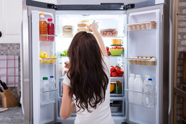 image of homeowner taking cold water bottle out of fridge depicting keeping cool naturally