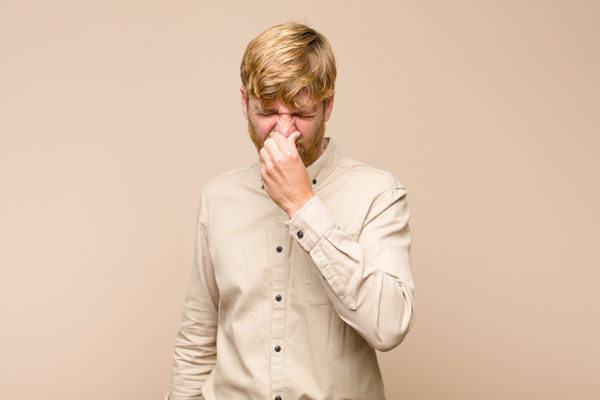 image of person plugging nose due to dead animal in hvac air duct