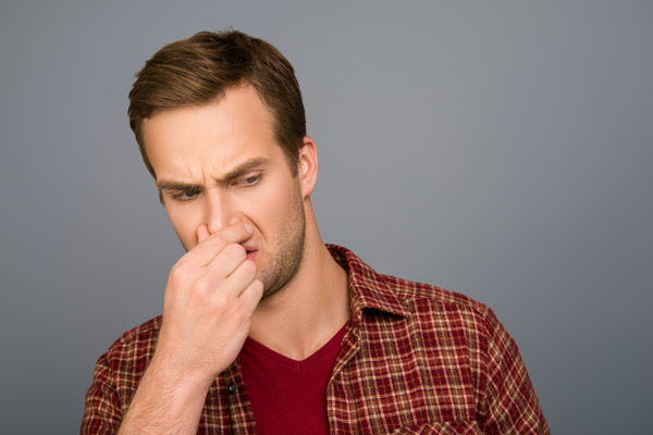 man plugging nose due to smelly air conditioner