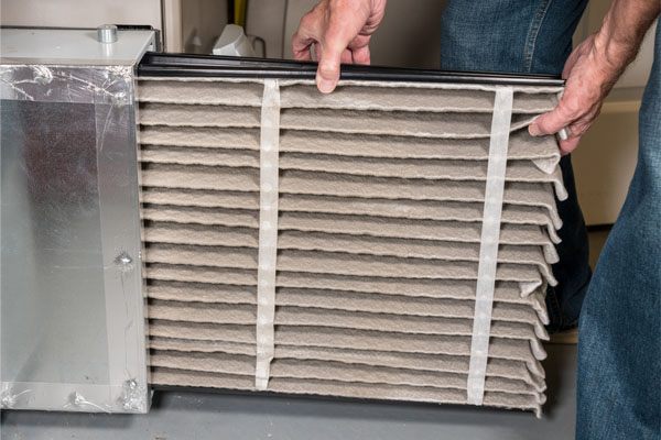 senior man changing a dirty air filter in a furnace