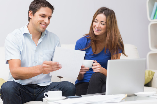 smiling couple paying their energy bills online at home