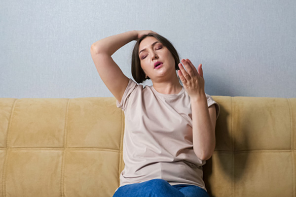 woman suffering from heat at home depicting discomfort with window cooling unit