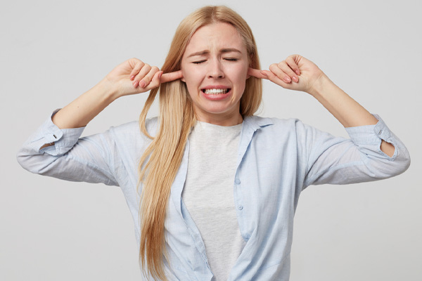 young homeowner covering ears due to air conditioner making noise when starting